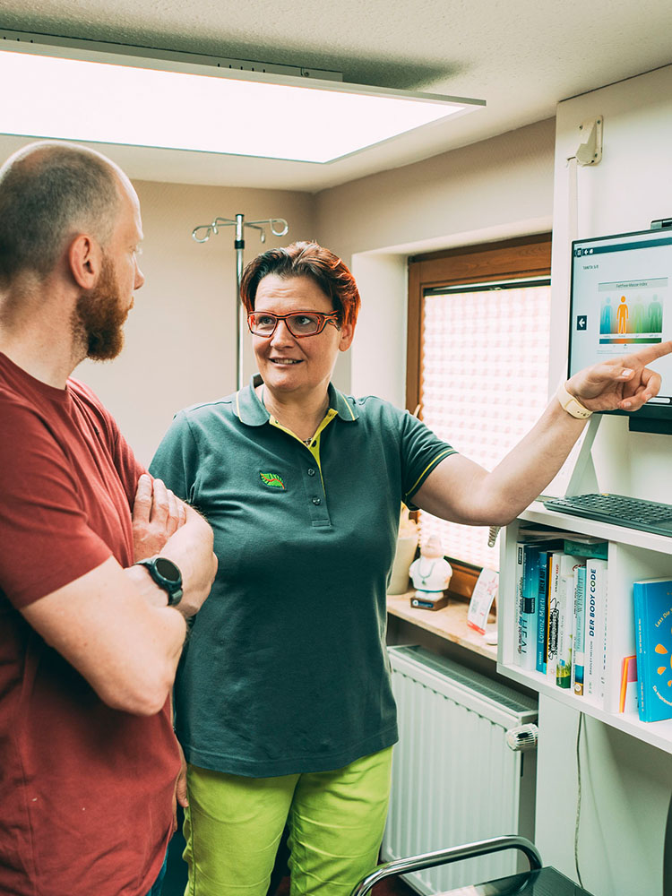 Zahnarztpraxis: Patientengespräch über Zahnbehandlung am Monitor.