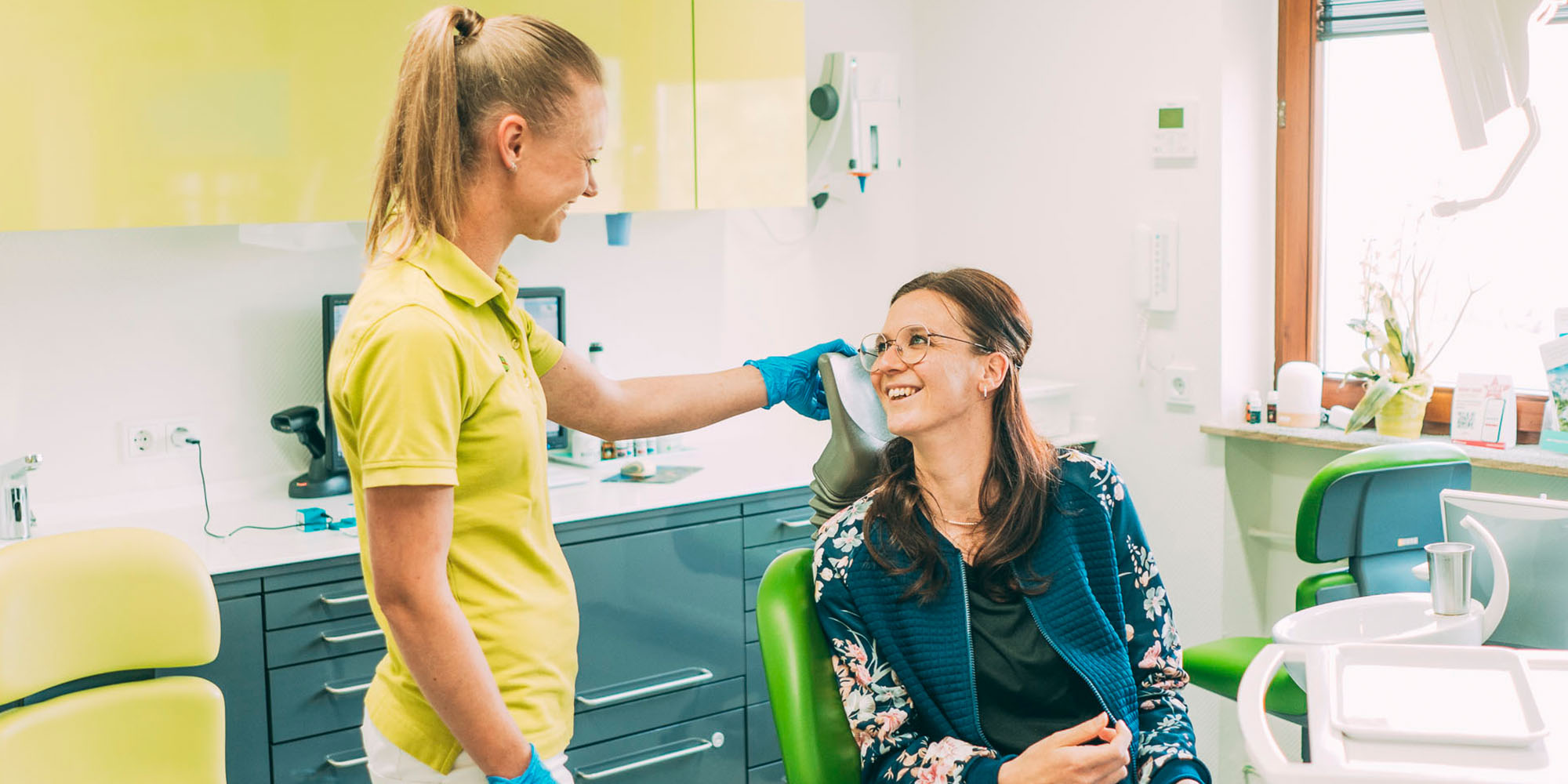Freundliches Zahnarztteam betreut Patientin in moderner Zahnarztpraxis für optimale Mundgesundheit.